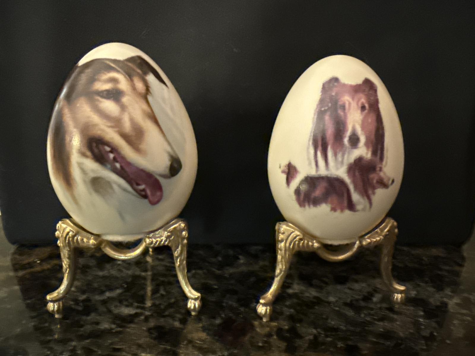 Two painted eggs with collie images on gold stands.