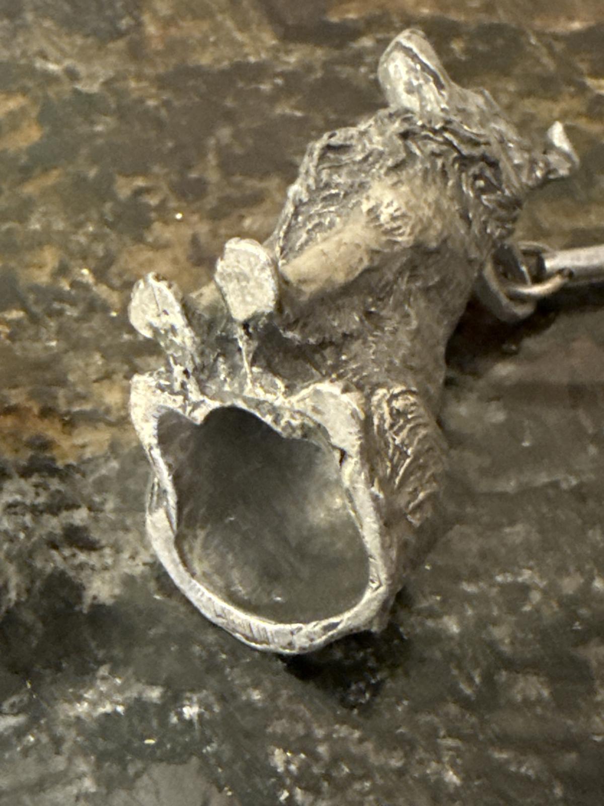 Underside view of metal collie sculpture on candle snuffer.