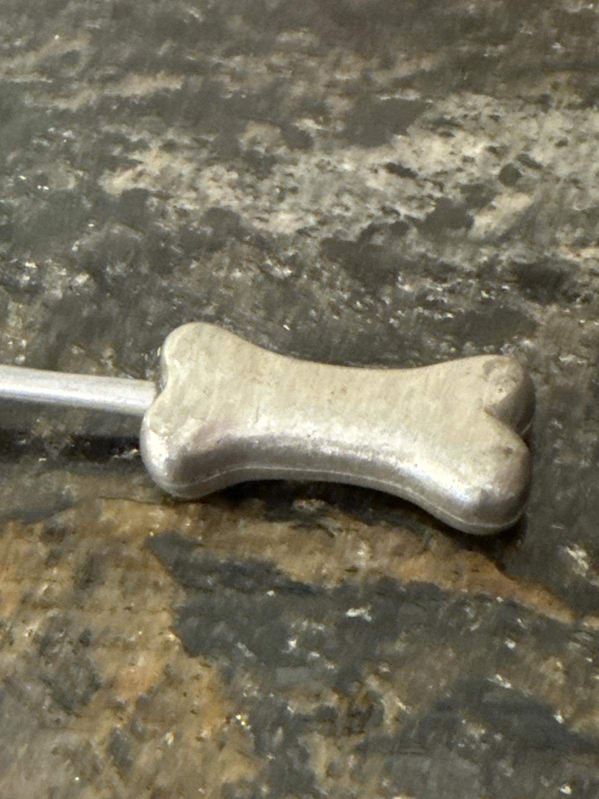Close-up of bone-shaped handle on candle snuffer.