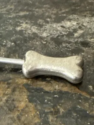 Close-up of bone-shaped handle on candle snuffer.