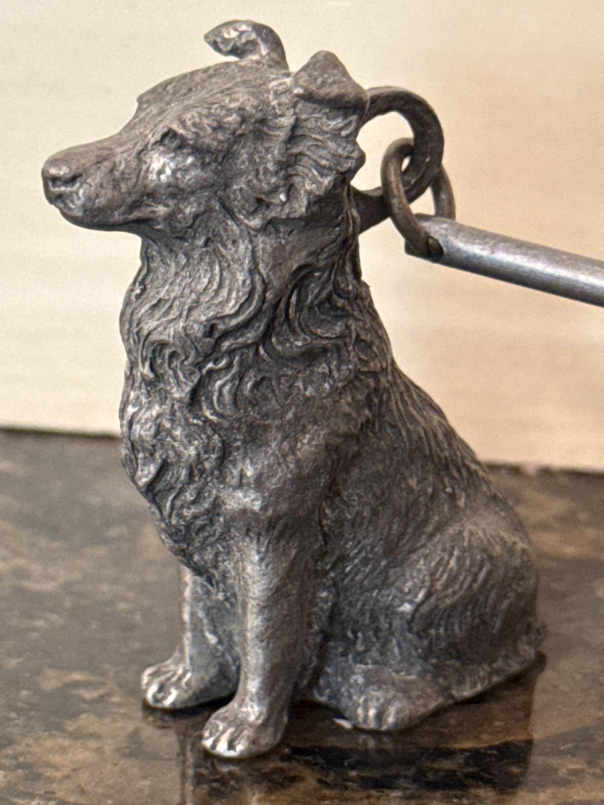 Close-up of metal collie sculpture on candle snuffer.