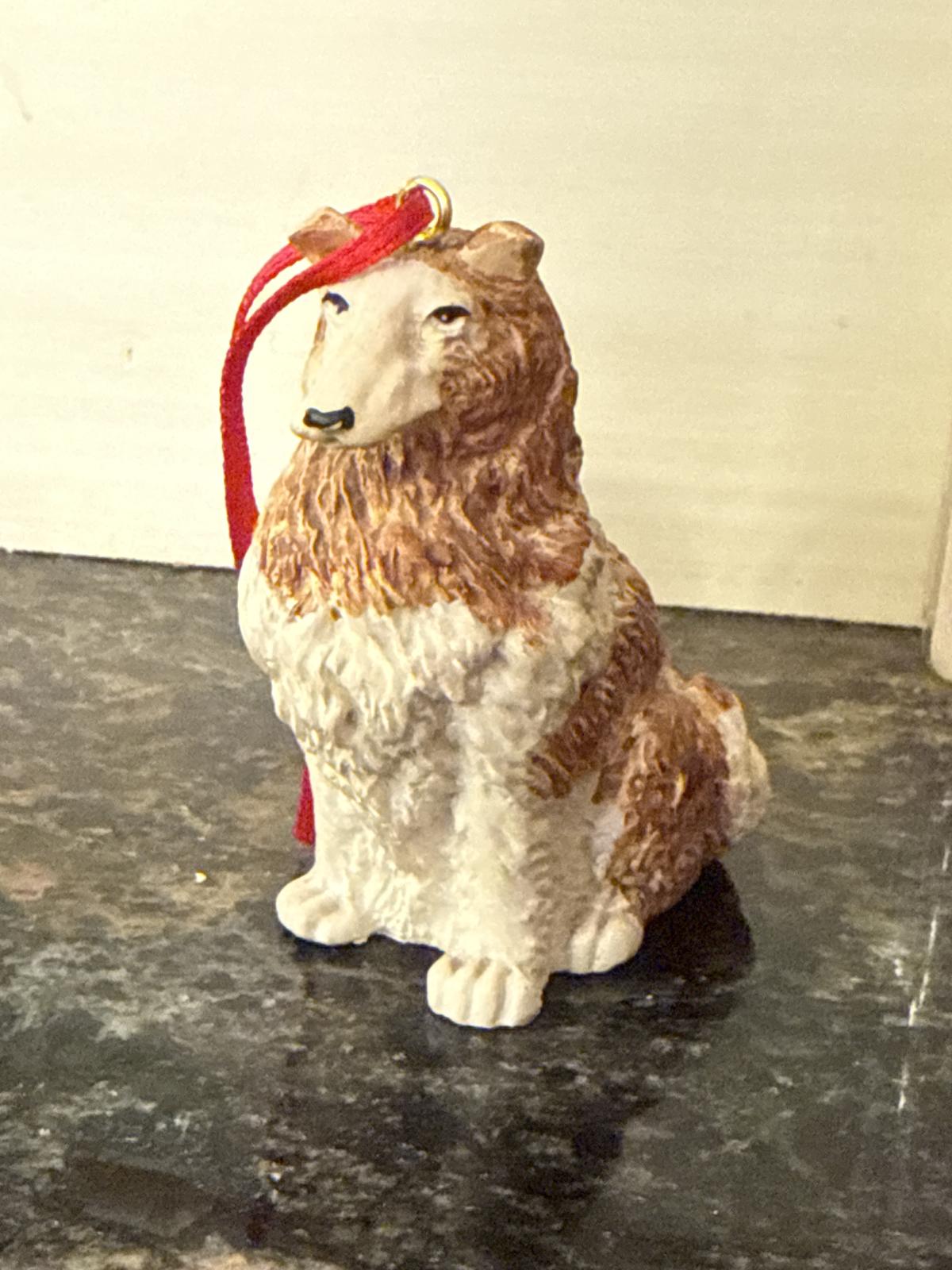 Close-up of collie dog ornament with red ribbon.