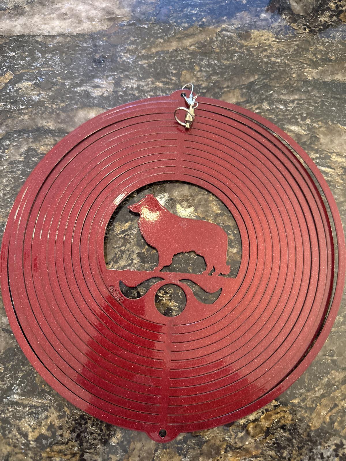 Red circular wind ornament with animal cutout and hanging hook.