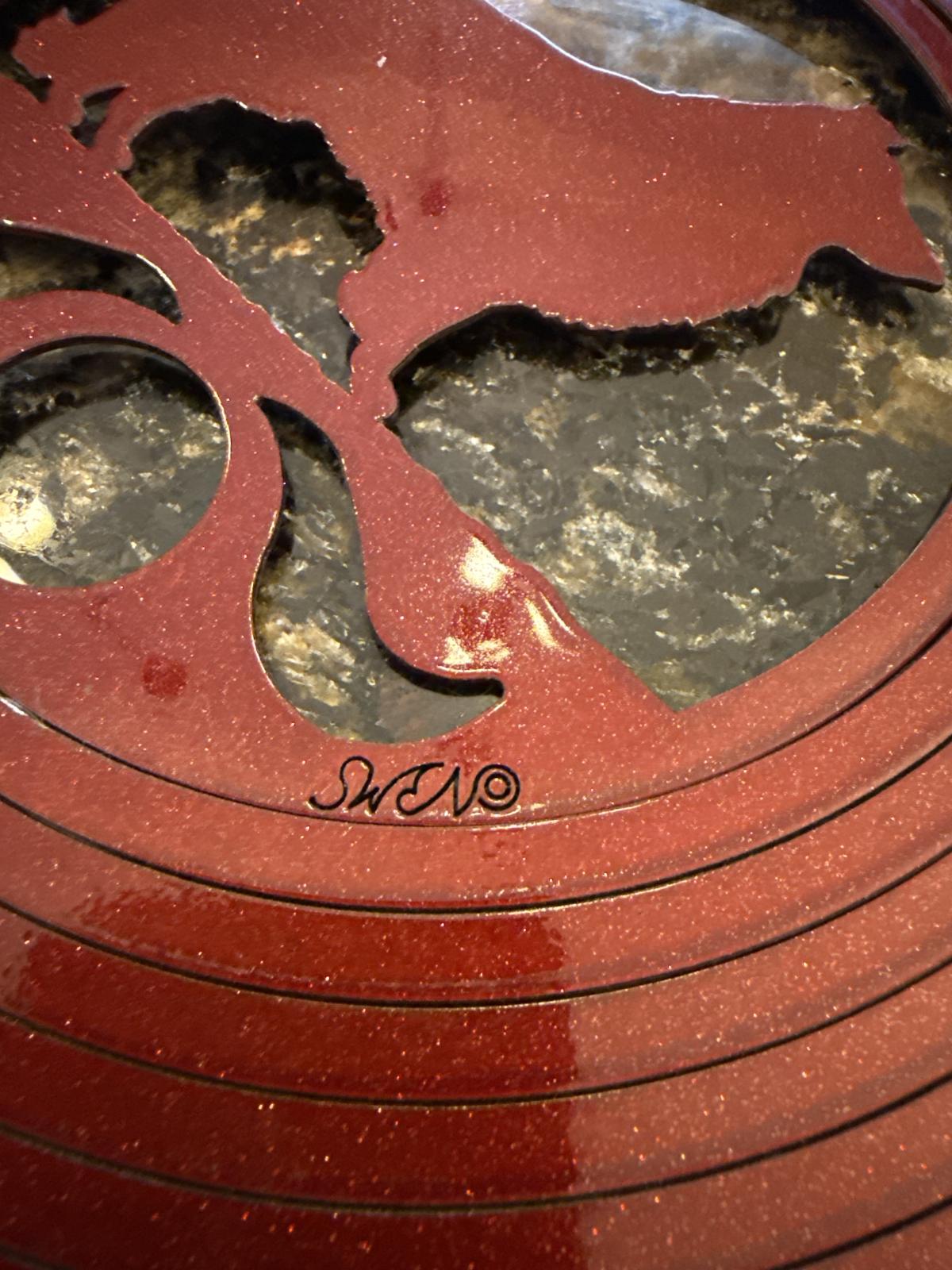 Close-up of red wind ornament with 'SWN' maker's mark.