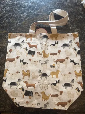 Canvas tote bag with dog pattern and handles on a stone surface.