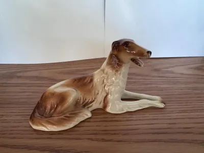 Porcelain Borzoi dog figurine, brown and cream, on a wooden surface.
