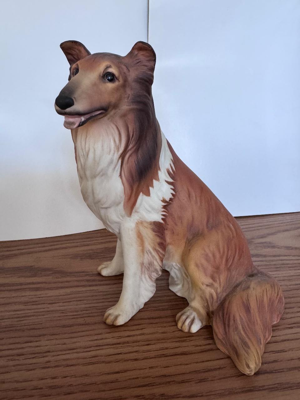 Ceramic collie figurine with brown and white colors, sitting on a wooden surface.
