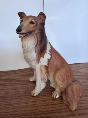 Ceramic collie figurine with brown and white colors, sitting on a wooden surface.